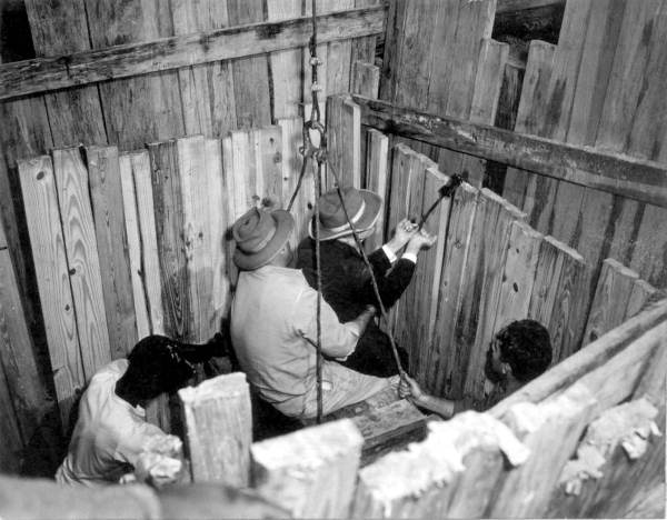 Contractor J.T. Conway holds treasure hunter George B. Mobley on his lap as a crane lowers them both into an open shaft in Green Cove Springs. Mobley is seen holding his 