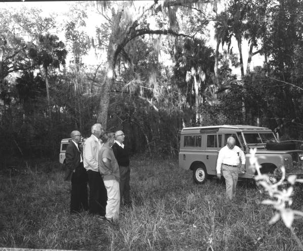 A group of Disney representatives inspecting the company's new property near Orlando and Kissimmee. The man at center in a dark sweater and glasses is Roy Disney, Walt Disney's brother (circa 1965).