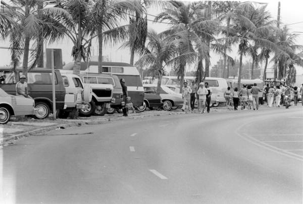 Parked cars line N. Roosevelt Street in Key West, Florida, as hundreds of Cuban exiles walk to nearby Garrison Bight Marina with the intention of retrieving family members in Mariel, Cuba. Photograph by Dale McDonald, 1980.