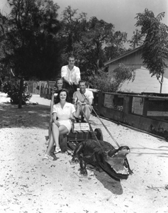 Two men and two women posing with a concrete alligator (1950s)