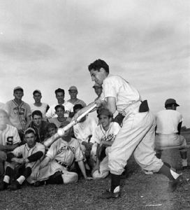 Phil Rizzuto, N.Y. Yankees bunting wonder, illustrates his unusual bunting "twist" before boys on bench: Bartow, Florida (1948)