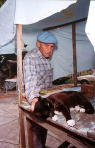 Mario Sanchez taking a break from his art work to pet his cat: Key West, Florida (1992)