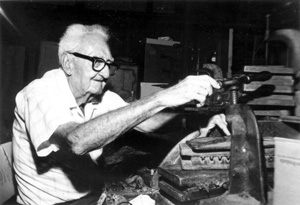 Rex Shaw turning press on cigars at his store on Fleming Street: Key West, Florida (197-)