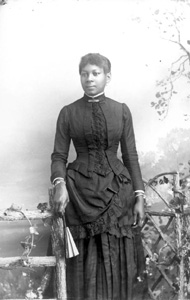 Woman in dark dress, holding a fan