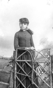 Girl holding a fan standing behind a gate