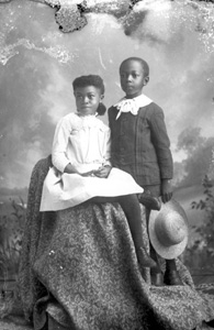 Seated girl and boy holding hat