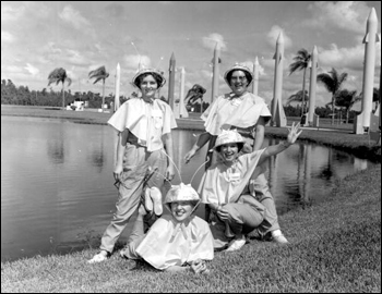 Sales representatives in "spacettes" costume pose before the rocket entranceway of Tupperware Home Parties Inc.: Orlando, Florida (1960)