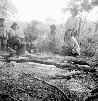 Four Seminole girls on a cattle roundup waiting for coffee by a campfire (195-)