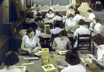 Women banding cigars, wrapping them in cellophane, and boxing them (192-)