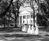 Young women wearing gowns pose before The Grove - Tallahassee, Florida.