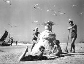 Three girls making a "sandman" at the beach.