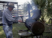 Norman West cooking country sausage links on a homemade barbecue grill for the VIDA Ranch crew lunch in Osecola County, Florida.