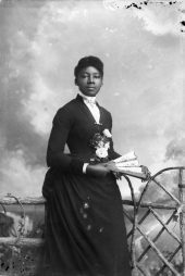 Woman wearing dress with roses on bodice and holding a fan.