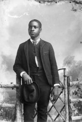 Man holding hat wearing suit.