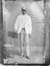 Man in white coat, with tilted hat and cane.