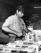 Florida State Senator D. Robert Graham sealing packages of paper napkins in a factory.